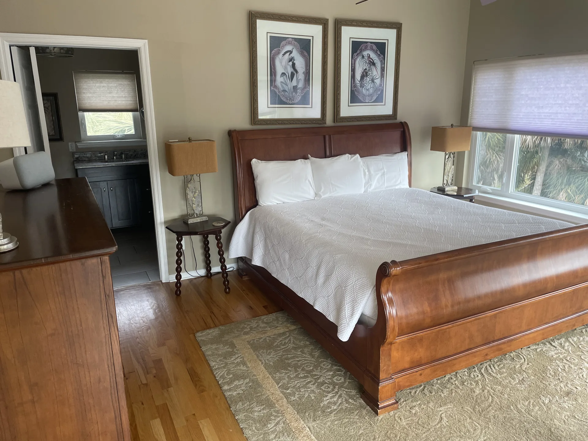 Master suite with cherry sleigh king bed, ensuite bath visible, and shell artwork